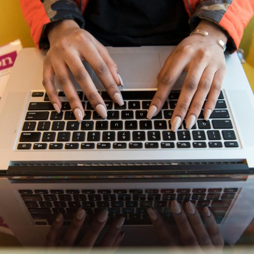A person typing on a laptop with a Python programming book visible, capturing technology and learning.