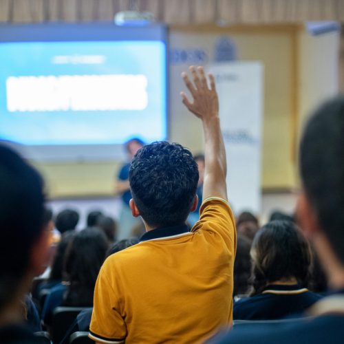 A student raises his hand during a seminar in an educational setting.